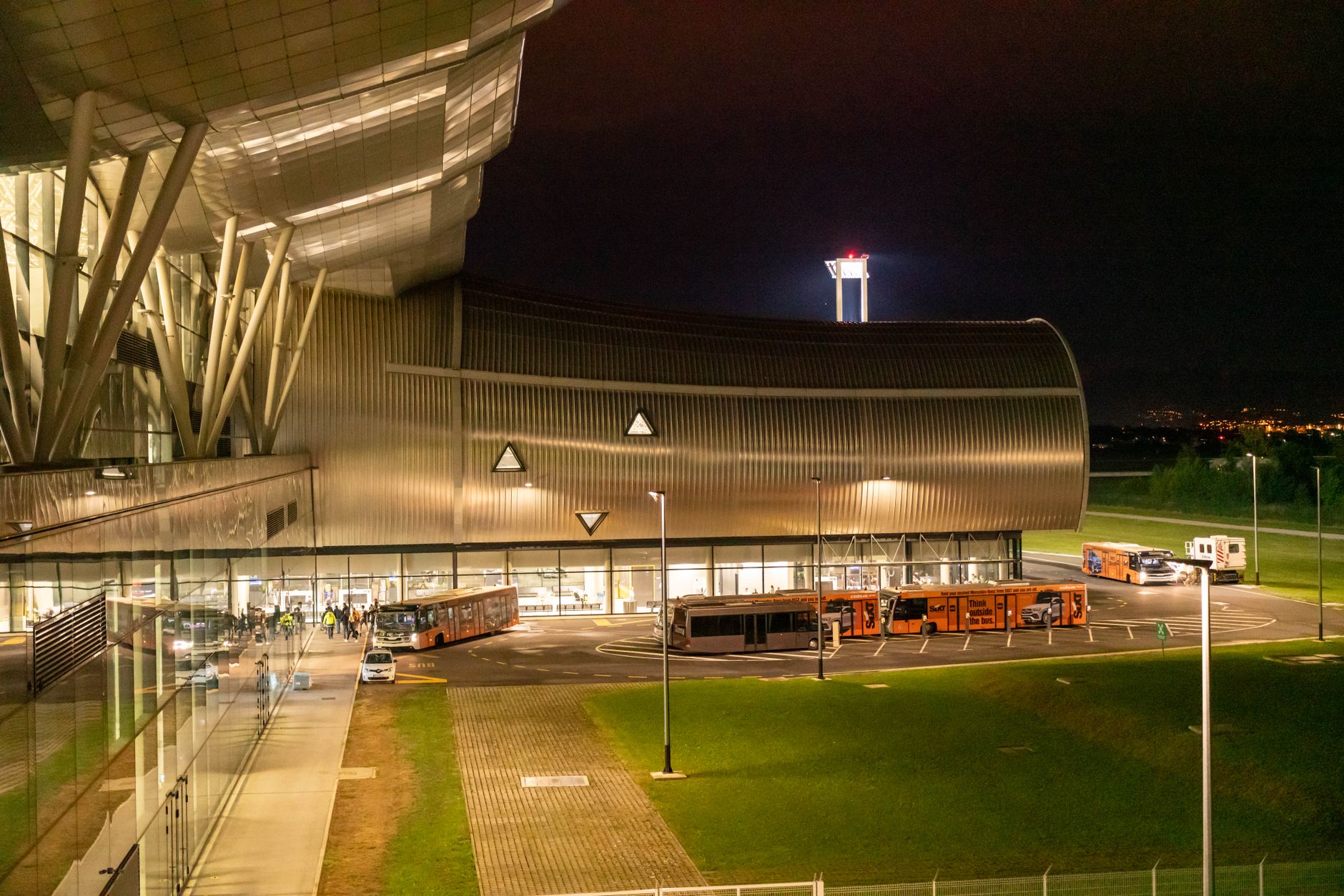 Contemporary building exterior with buses at night, highlighting urban transport hub.